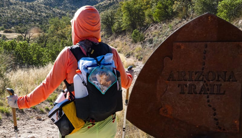 Rear view of hiker wearing Outdoor Vitals Skyline 30 Fastpack on Arizona Trail with trekking poles, water bottles, and trail gear.