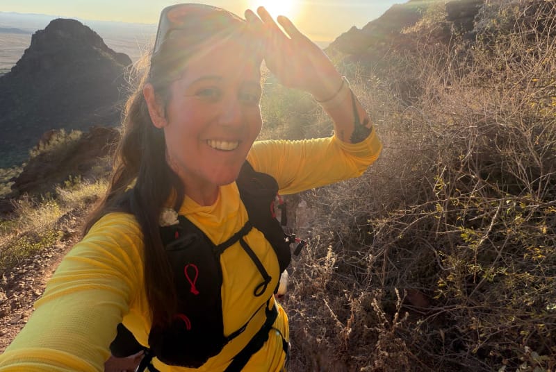 Hiker wearing Outdoor Vitals Skyline 30 Fastpack during sunny desert ascent, showing front harness pockets and lightweight fit.