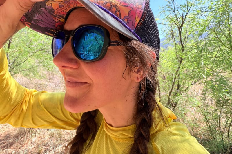 Close-up portrait of woman wearing Ombraz Blue Mirror sunglasses during a desert hike in Arizona.