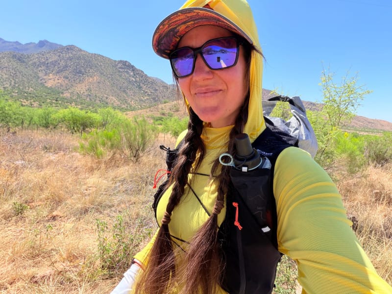 Woman hiking in the Sonoran Desert wearing the Hyperlite Mountain Gear Pemi 15 ultralight daypack during a sunny desert trail hike.