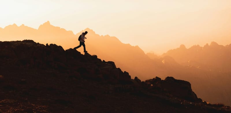Hiker silhouetted on a rocky desert ridge at sunset while testing the best trail runners and hiking shoes for desert hiking and backpacking in 2026.