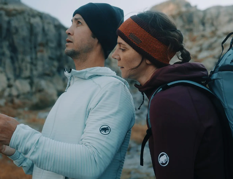 Two hikers wearing Mammut fleece layers while hiking in a rocky mountain landscape.