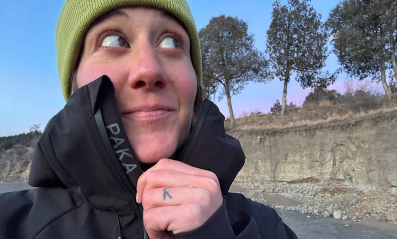 Hiker wearing a black PAKA insulated winter jacket and beanie in cold weather.