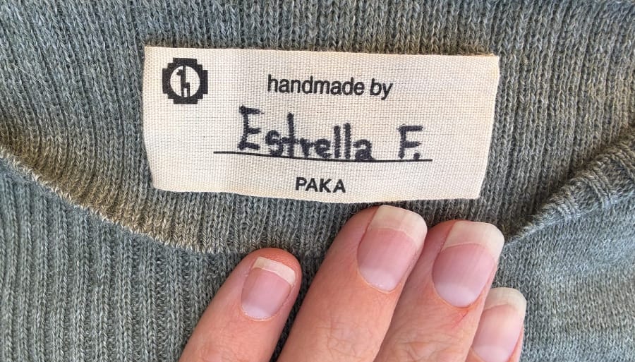 Close-up of a PAKA alpaca wool garment with a handmade-by artisan label sewn inside.