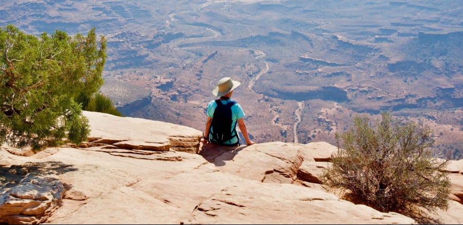 Hiker sitting on a sandstone overlook during a desert hike with an ultralight backpack.