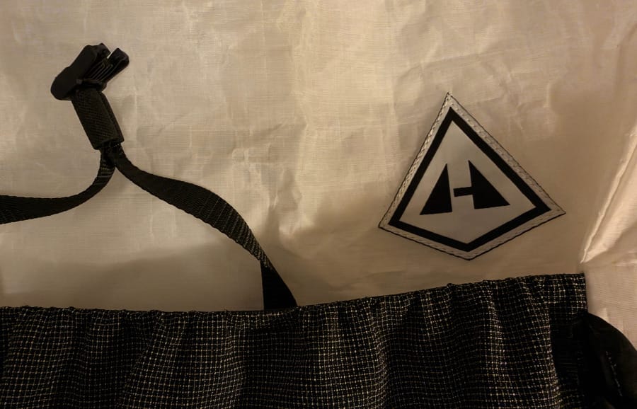 Close-up of the Hyperlite Mountain Gear logo on the white Dyneema Composite Hybrid fabric of the Aero 28 ultralight backpack.
