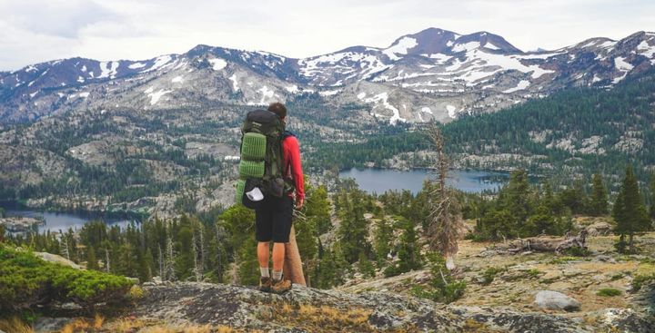 a hiker in a vast mountain landscape wearing a backpack and one of the top picks for best hiking socks of 2026