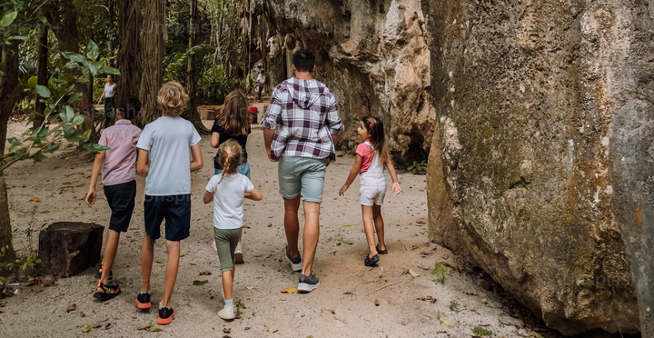 a family with many kids going for a hike on a nice wild hiking trail and all the children look very happy.