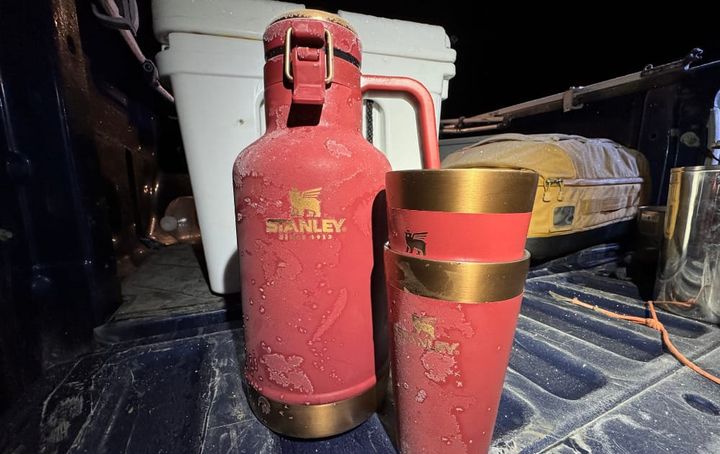 Classic Easy-Pour Growler 64oz By Stanley sitting on the tailgate of a truck in freezing cold conditions during a road trip
