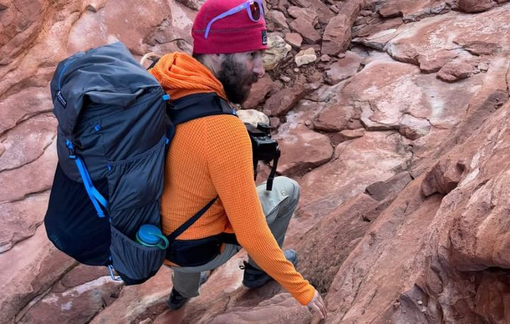 a backpacker hikes in a canyon wearing a loaded up Mariposa 60 Backpack By Gossamer Gear