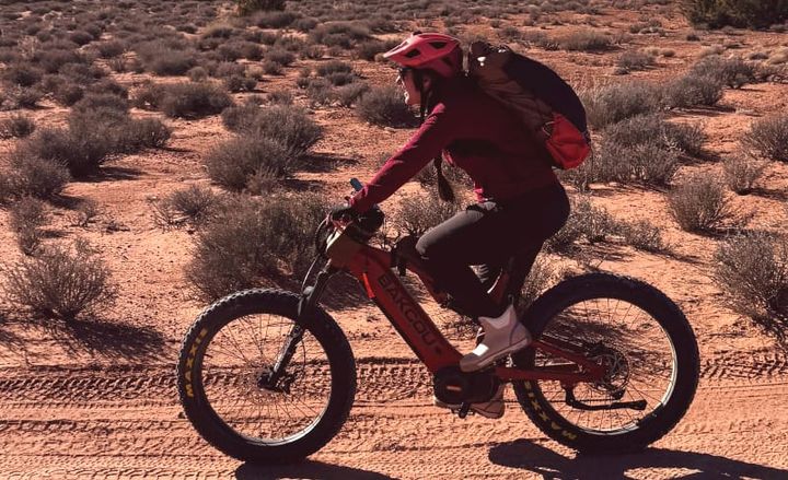 a backpacker riding the Scout Full Suspension eBike By Bakcou in the southwest to a trailhead in red rock country