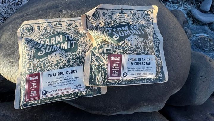  Farm to Summit dehydrated backpacking meals displayed on a rock surface, featuring colorful compostable packaging and locally sourced ingredients.
