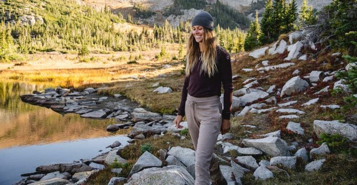 a hiker wears the Everyday Joggers by PAKA at camp in the mountains near a lake because the alpaca wool is warm and durable