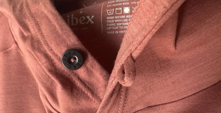  Macro image of the Springbok Hoodie showing Ibex-branded button, tag, and fabric texture up close.