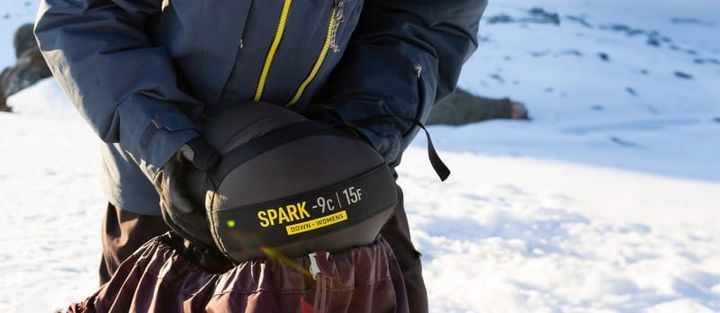 backpacker using sea to summit spark sleeping bag in a snowy mountain scene