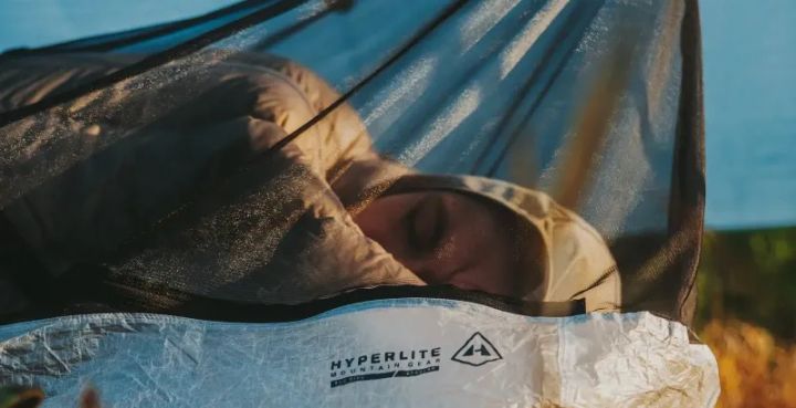 Person sleeping inside the Hyperlite Bug Bivy under a tarp, demonstrating breathable mesh and Dyneema floor
