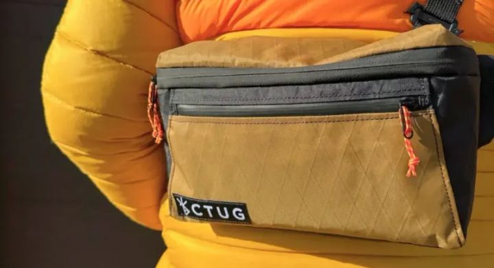  Close-up of a Chicken Tramper Ultralight Gear fanny pack worn crossbody over a bright orange and yellow puffy jacket.