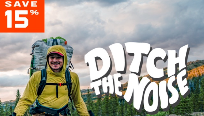  Smiling backpacker with Hyperlite Mountain Gear pack and trekking poles in a mountain landscape with text overlay reading “Save 15%” and “Ditch the Noise.”