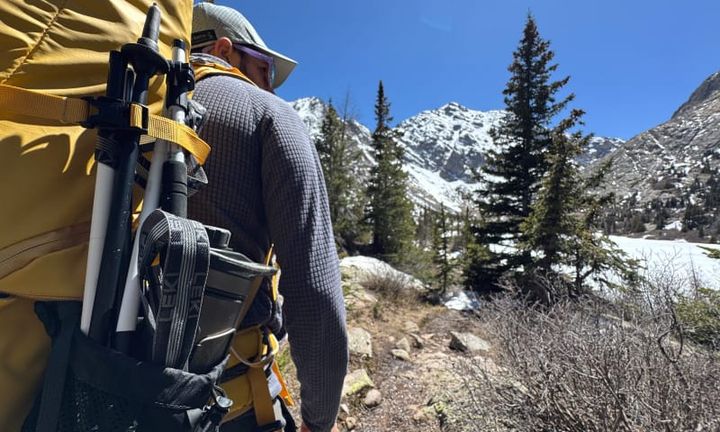 LEKI Skytera FX Carbon SL trekking poles stored on the side of a yellow backpack during an alpine hike in Colorado.