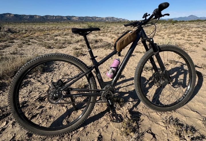  Full view of the Priority 600ADX mountain bike parked on arid desert terrain with distant mesas and clear blue skies.