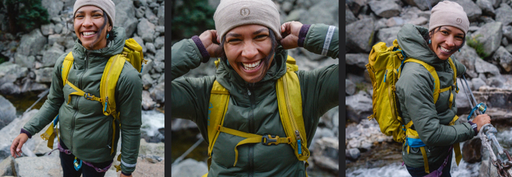  A hiker wearing the PAKA Apu Lightweight Puffy Jacket and a yellow backpack smiles during a rocky river crossing, showcasing the jacket’s fit and outdoor performance in a mountain setting.