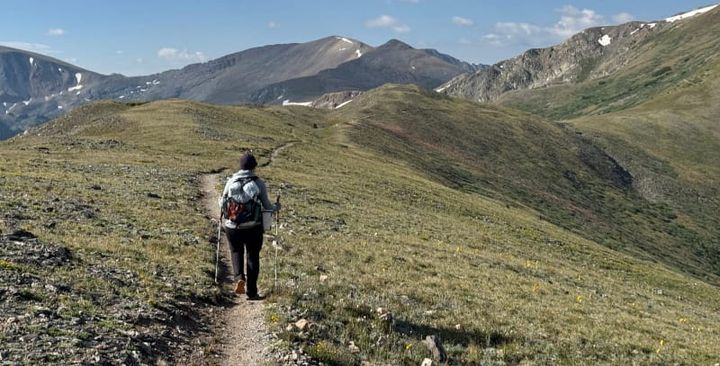 Hiker walking through alpine terrain wearing the new Hyperlite Windrider 40 backpack with updated features.