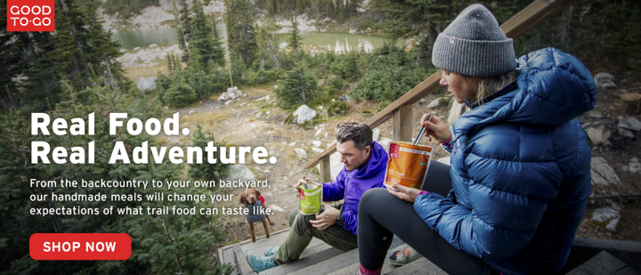 Two hikers in puffy jackets enjoy Good To-Go dehydrated meals on a mountain trail, promoting the 2025 Good To-Go Fall Sale offering 15% off sitewide with code FALL15.