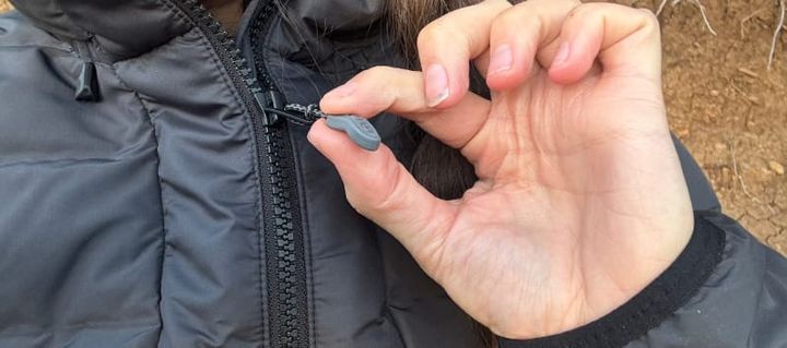 camper wearing the KUIU Elements Hooded Jacket outdoors, showing the hood and front zipper design during field testing.