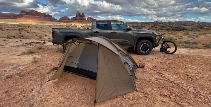 Snow Peak Minute Dome Pro Air 1 tent set up on red desert ground near a truck and mountain bike under cloudy skies.