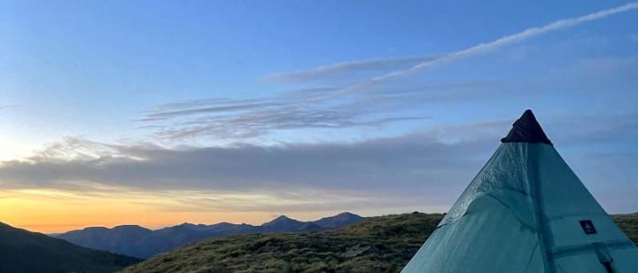 Ultralight solo backpacking tent set up on an alpine ridge at sunset, showing a lightweight pyramid-style shelter designed for solo backpacking