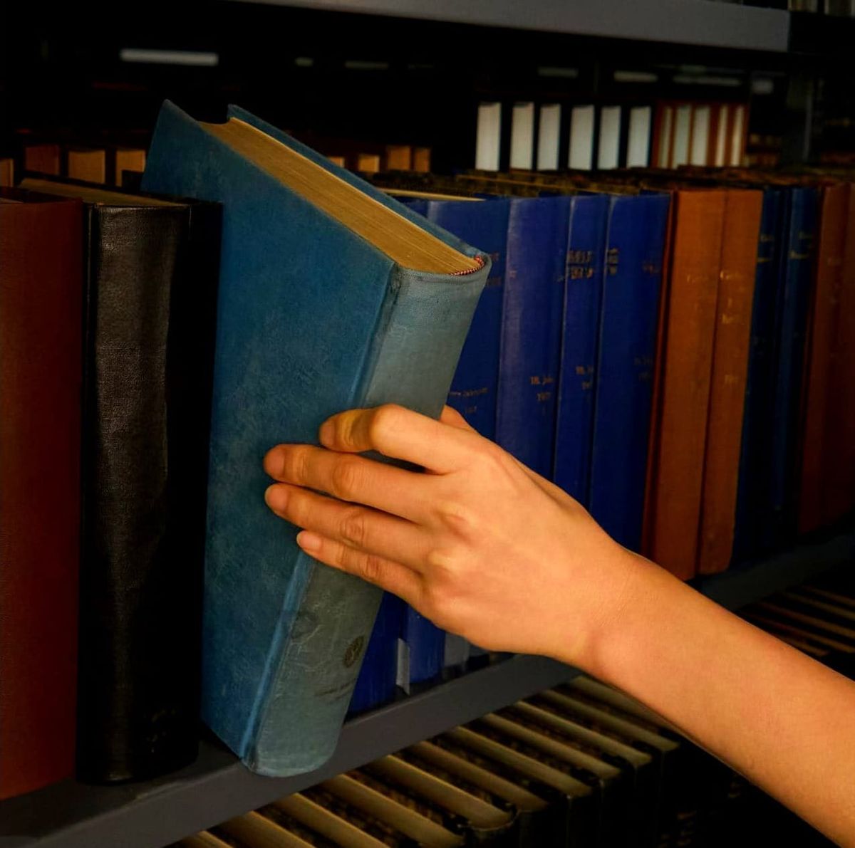 hand pulling book from library shelf