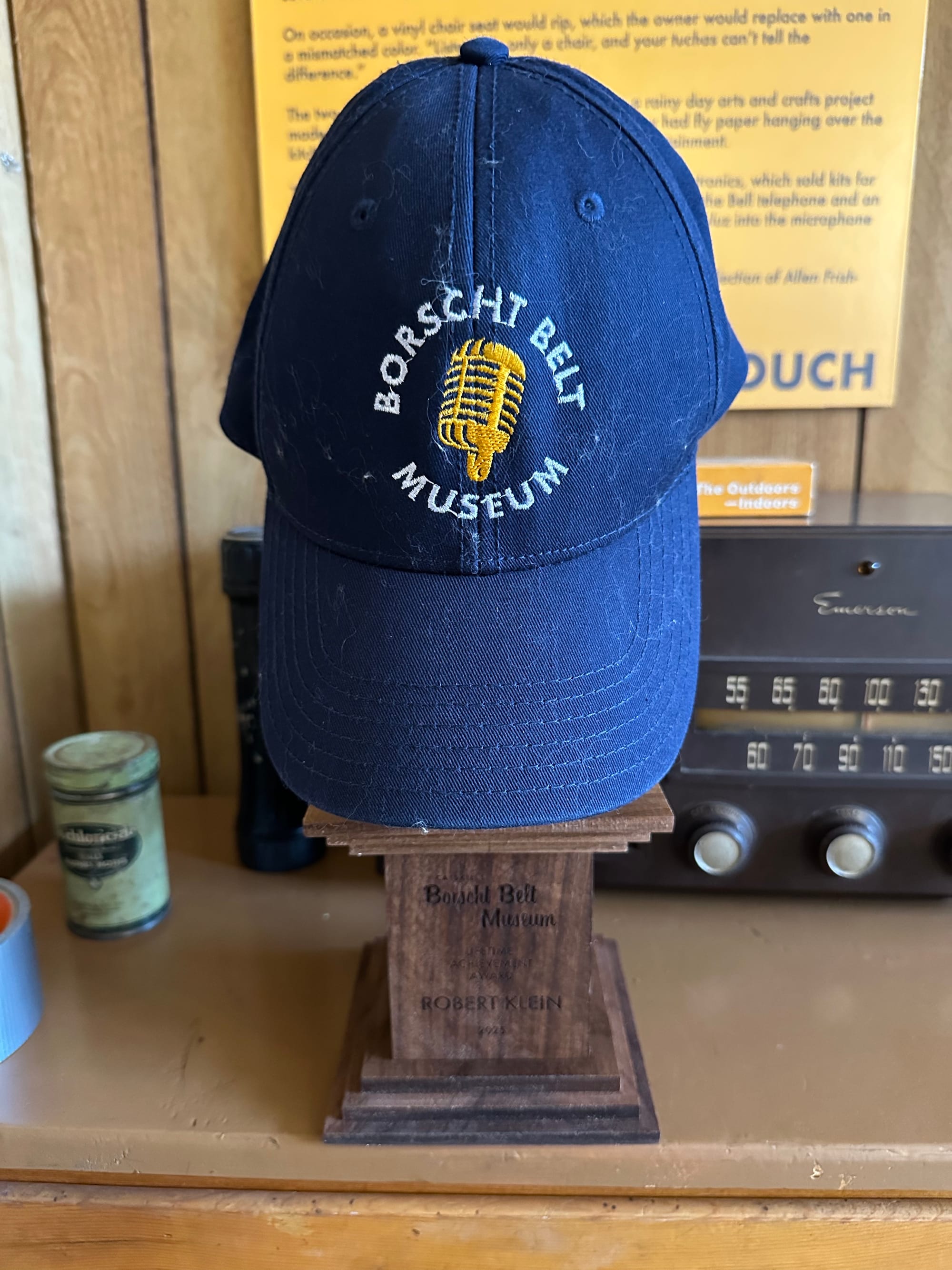 A Borscht Belt Museum baseball cap hanging off of Robert Klein's lifetime achievement award with the engraved base visible.
