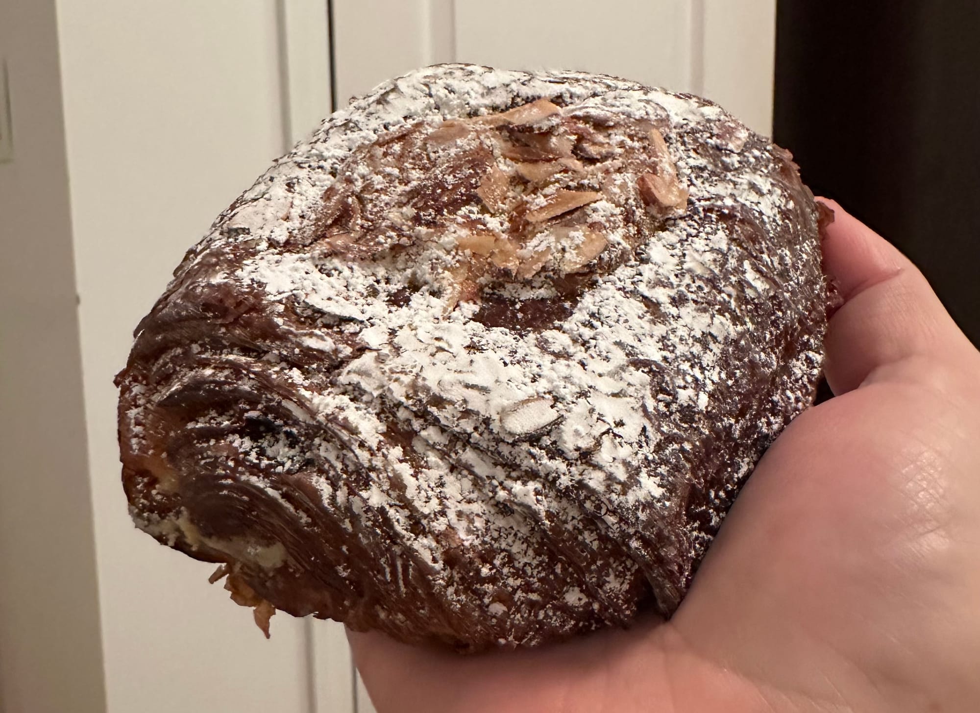 Big croissant topped with almond slivers and confectioners sugar.