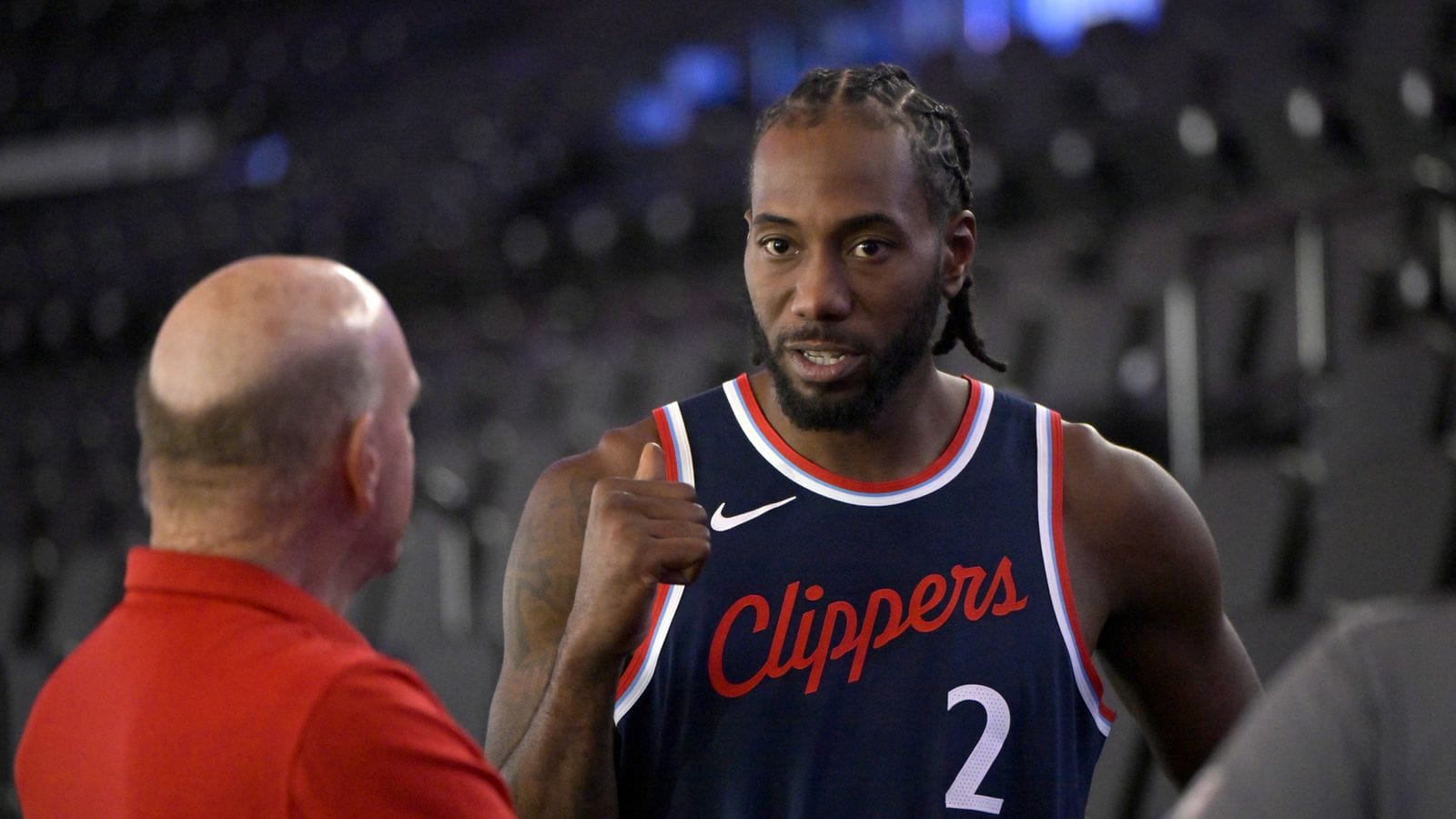 Kawhi Leonard in a Clippers jersey talking to Steve Ballmer who is facing away from the camera.