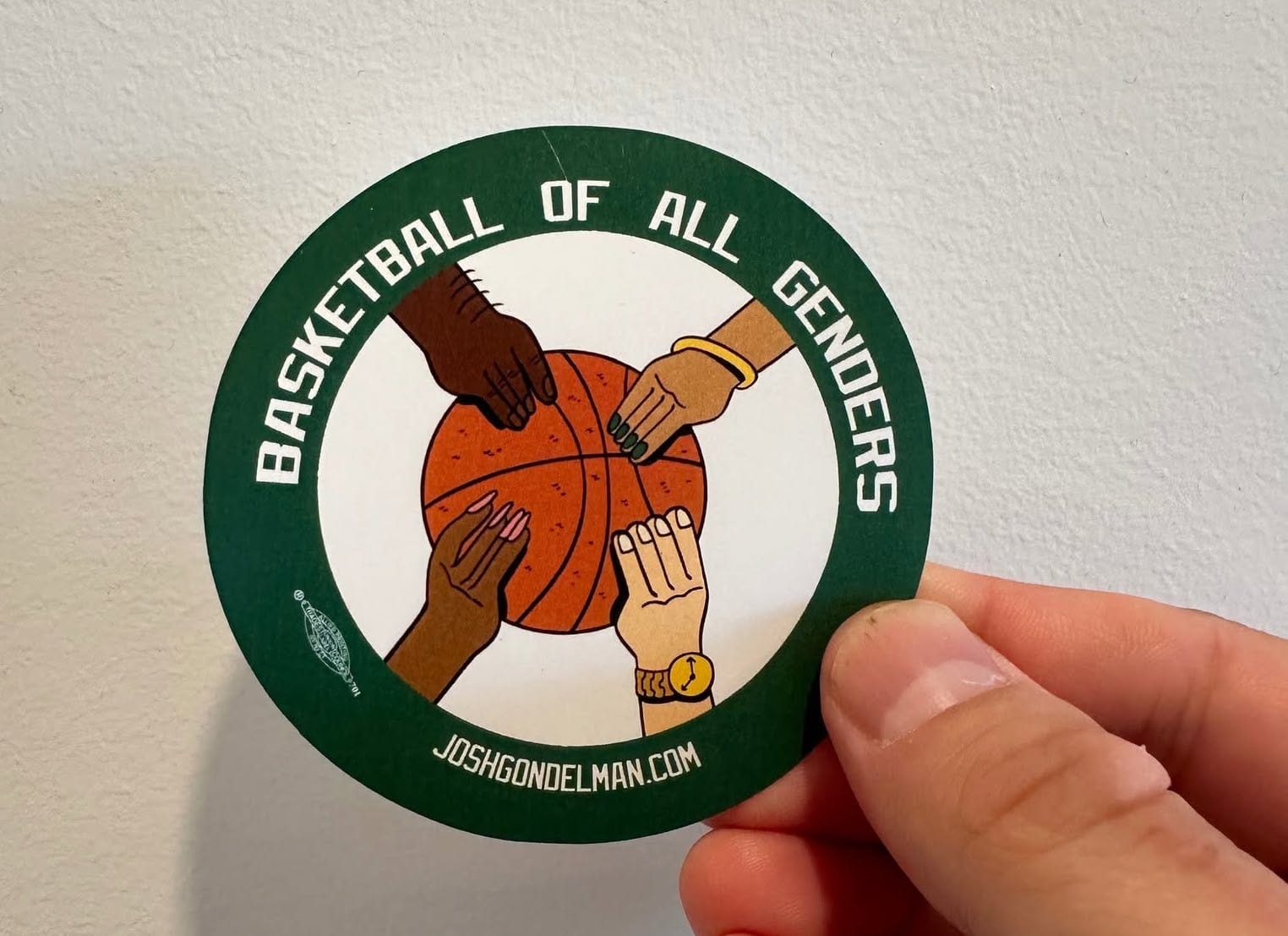 Sticker featuring four hands belonging to people of various genders holding a basketball with the slogan "BASKETBALL OF ALL GENDERS" plus my website and a union bug for Radix Co-Op.