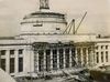 Black and white photo of the Great Dome (Building 10) of MIT under construction. The columns in the front of the building, and part of the dome, are covered with scaffolding.