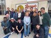 Photo of PBE alumni and spouses standing and kneeling in front of a sign that says "Roscoe's House of Chicken and Waffles".