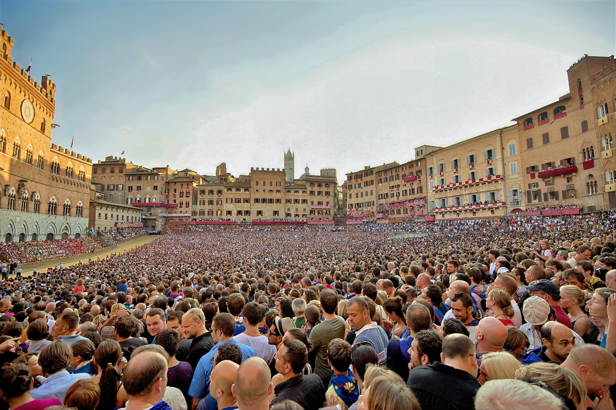 Piazza del Campo packed with crowds during the Palio di Siena, with the outer track covered in yellowish tufo clay for the race.