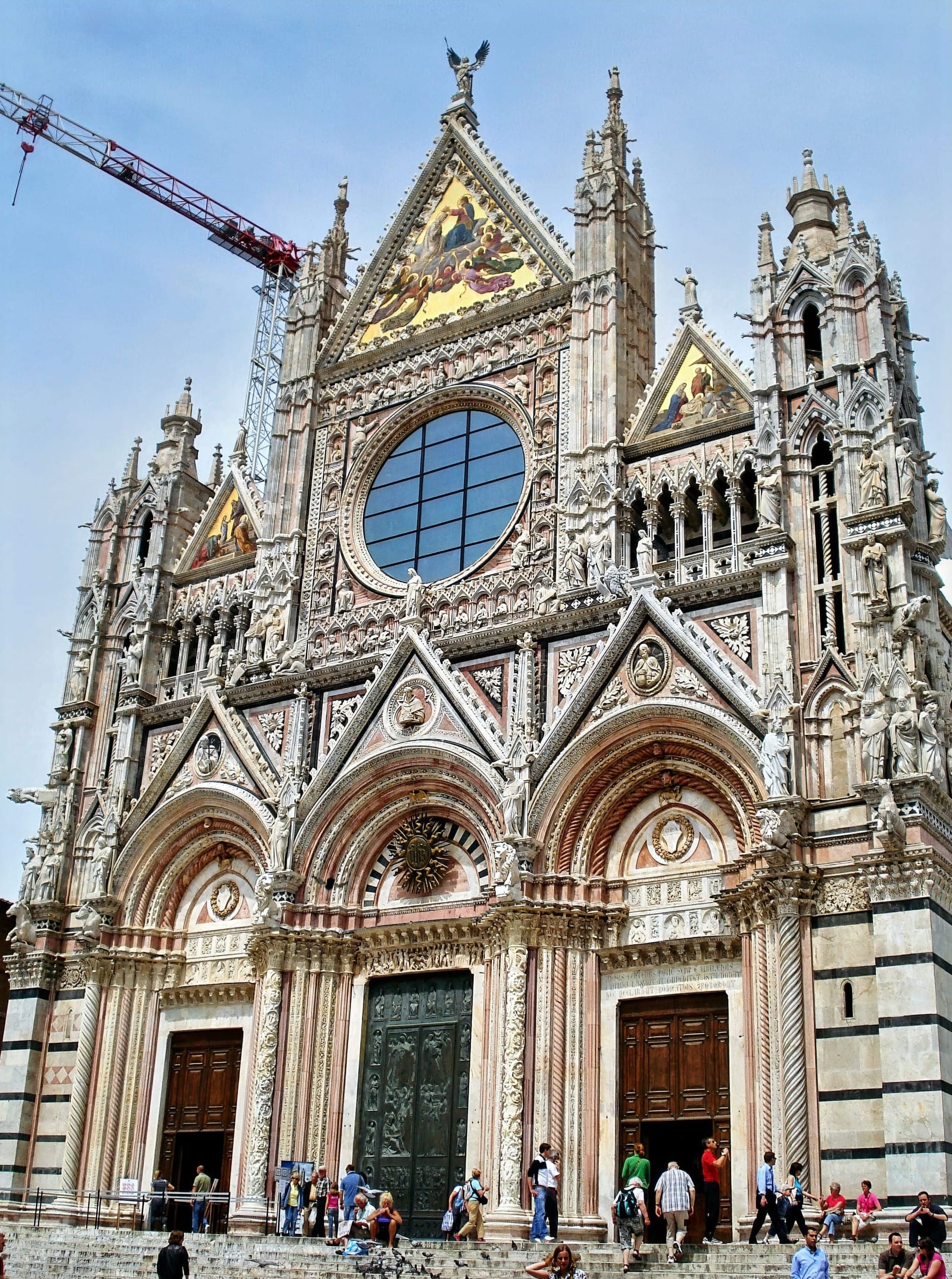The monumental stone facade of the Santa Maria della Scala complex facing the Siena Cathedral square.