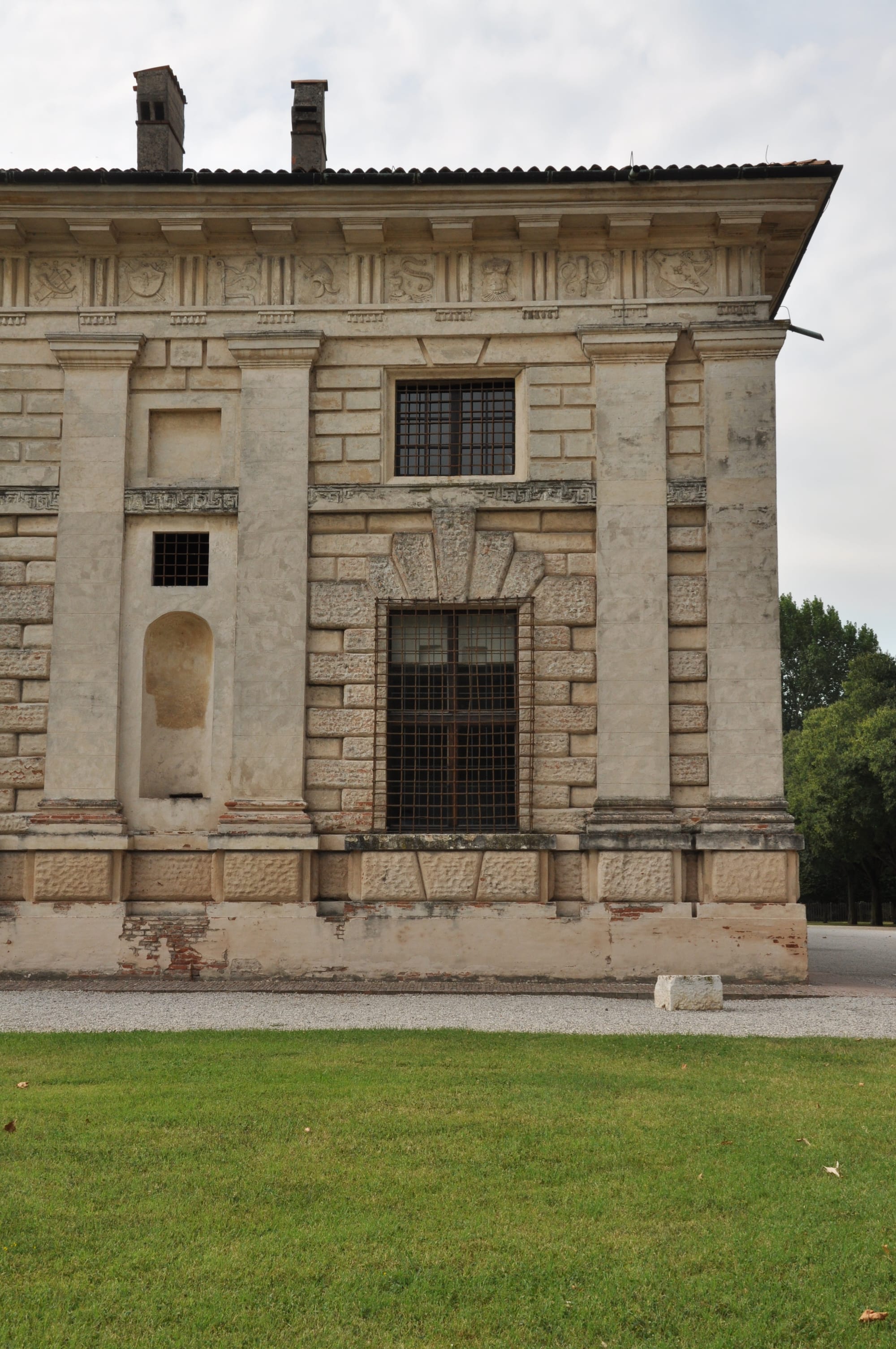 Close-up of the corner of the exterior facade, showing the texture of the plaster rustication and a rectangular window with grates.
