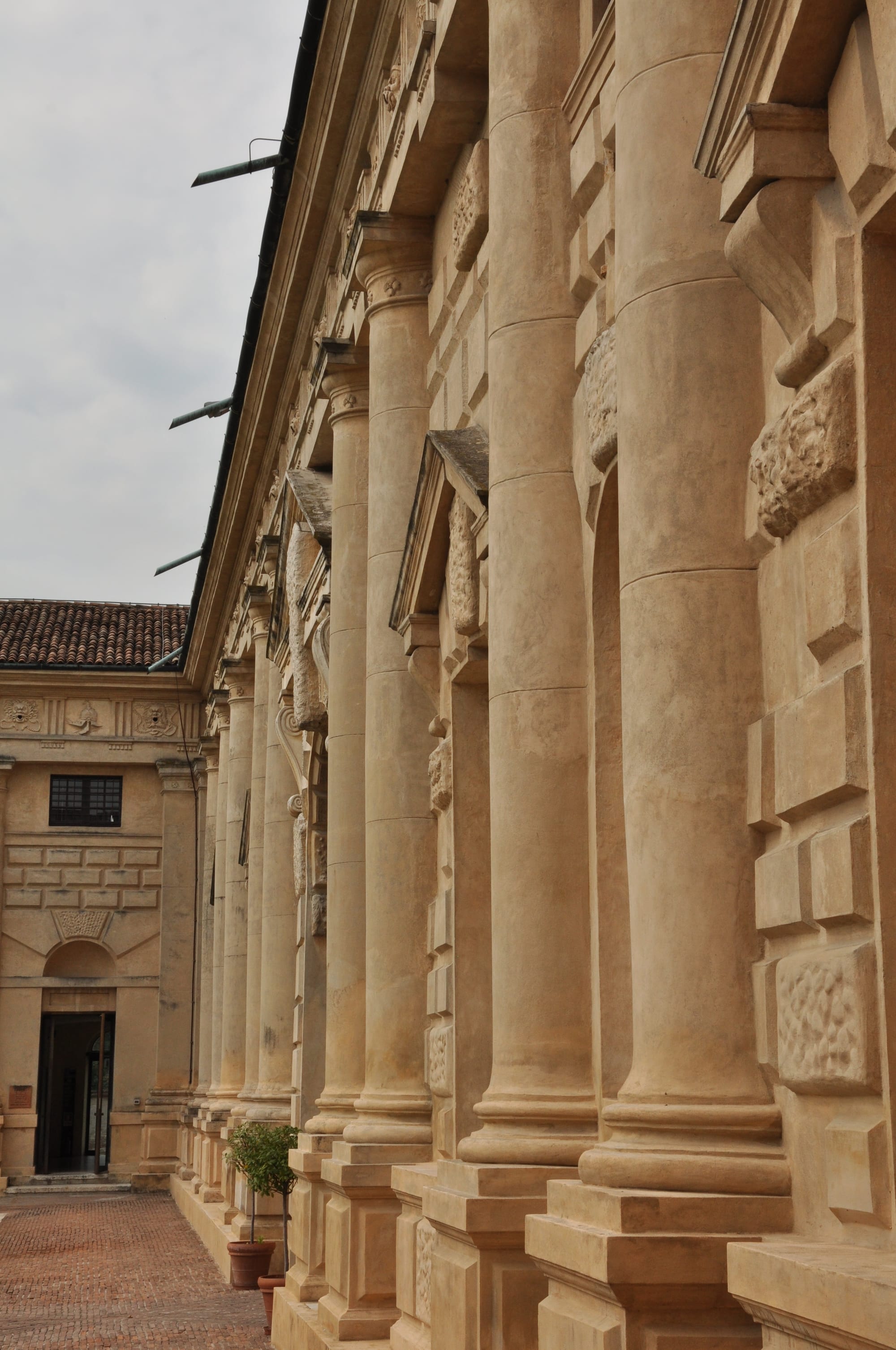 Angled perspective shot along the courtyard facade, highlighting a row of semicolumns and the upper frieze.