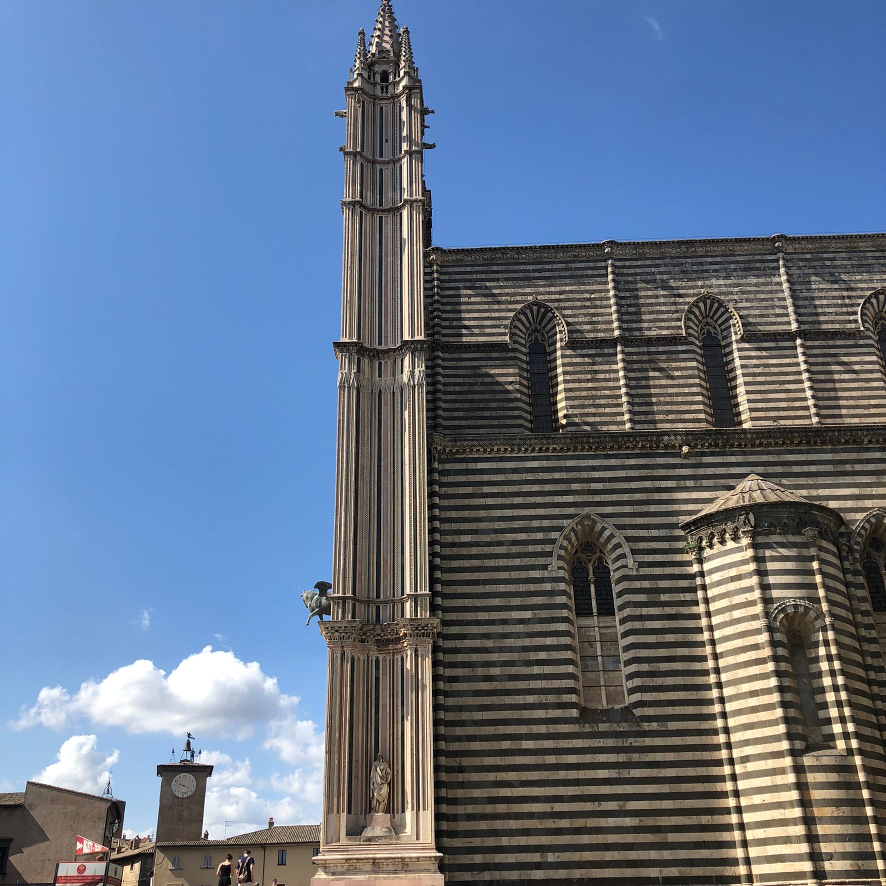 Profile view of the cathedral's corner, showing how the triangular spires of the facade stand independent of and higher than the roofline of the striped side wall.