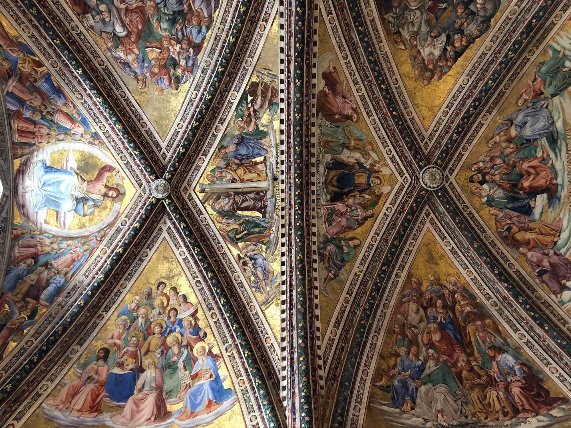 View looking up at the vaulted ceiling of the San Brizio Chapel, showing triangular segments covered in brilliant gold-leaf frescoes of religious figures.