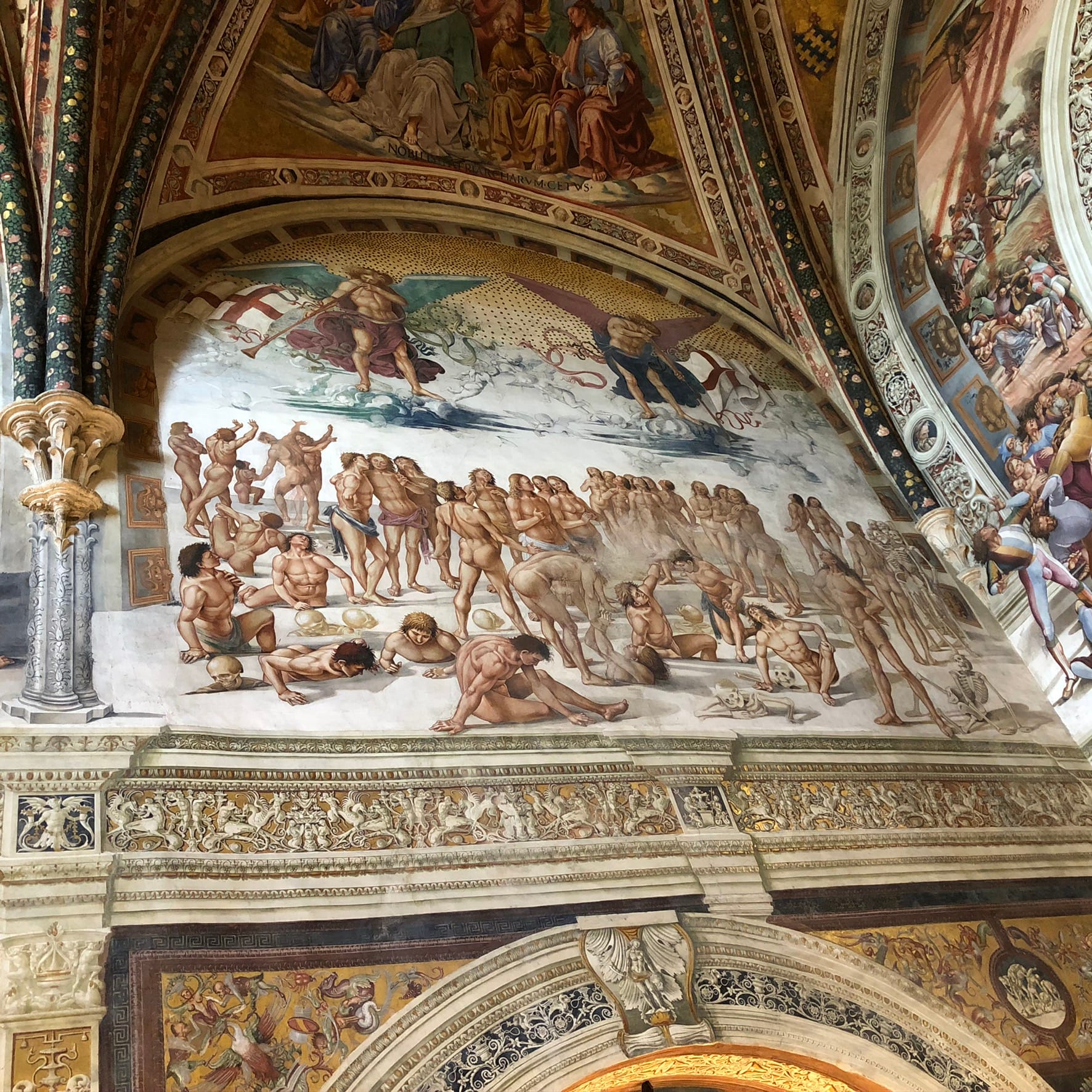 Fresco panel of muscular figures emerging from the ground during the Resurrection, with two large winged angels blowing horns against a cloudy sky.