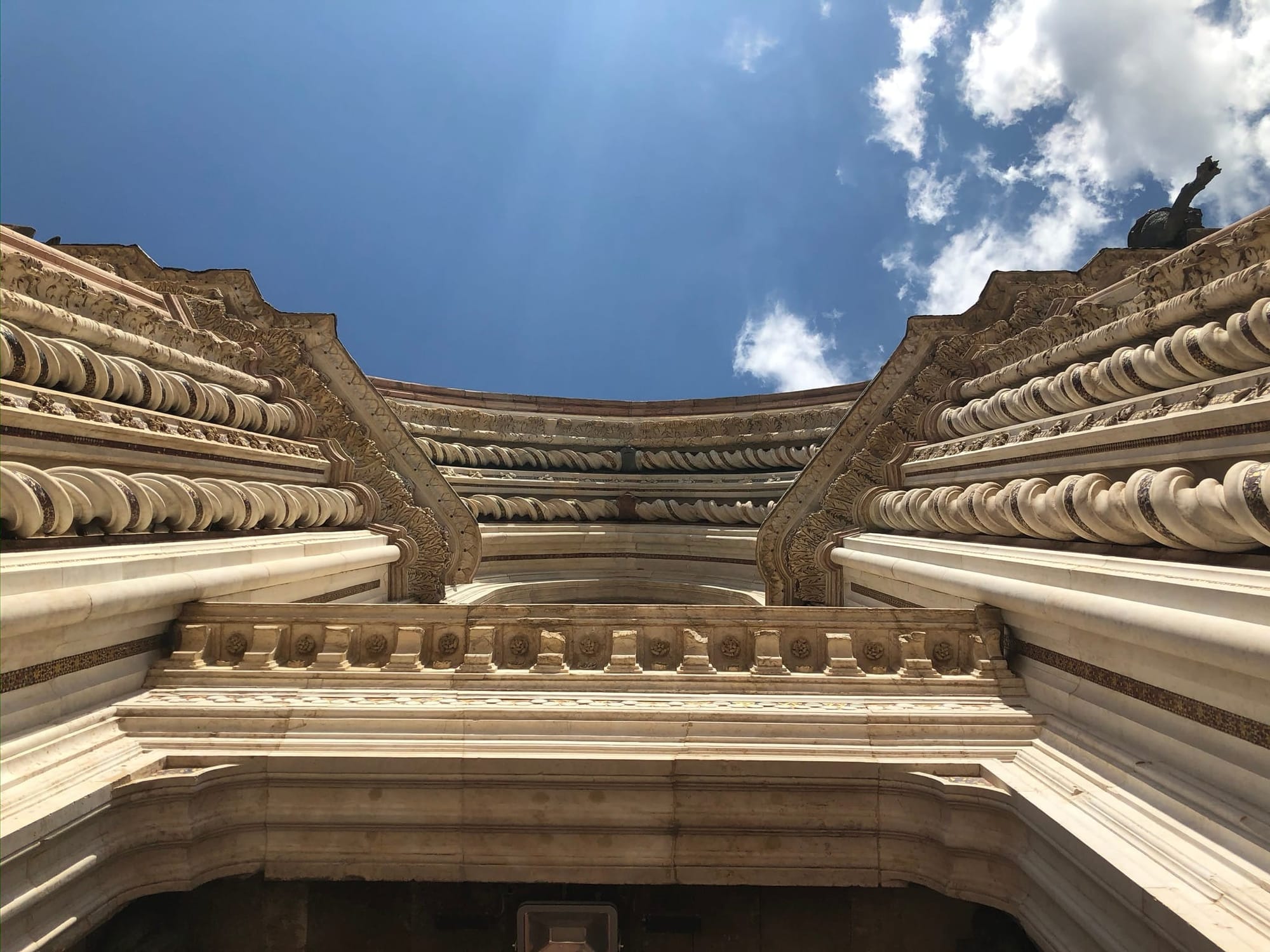 Vertical perspective looking up into the central entrance of the Duomo, highlighting the deeply recessed concentric arches and spiraling inlaid marble columns.