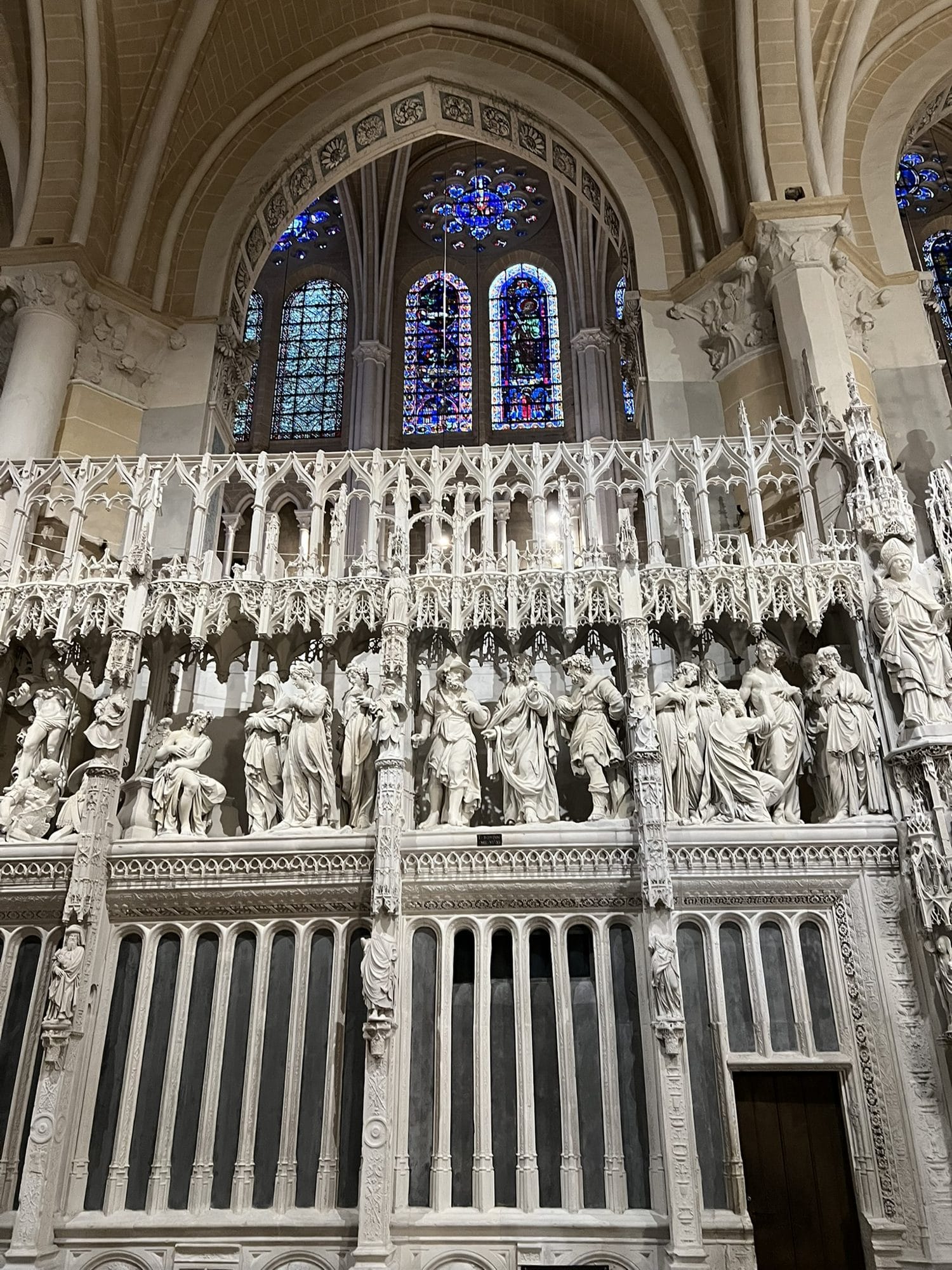 The choir screen of Chartres Cathedral, with statues and pinnacles in bright white stone and the blue windows of the ambulatory above