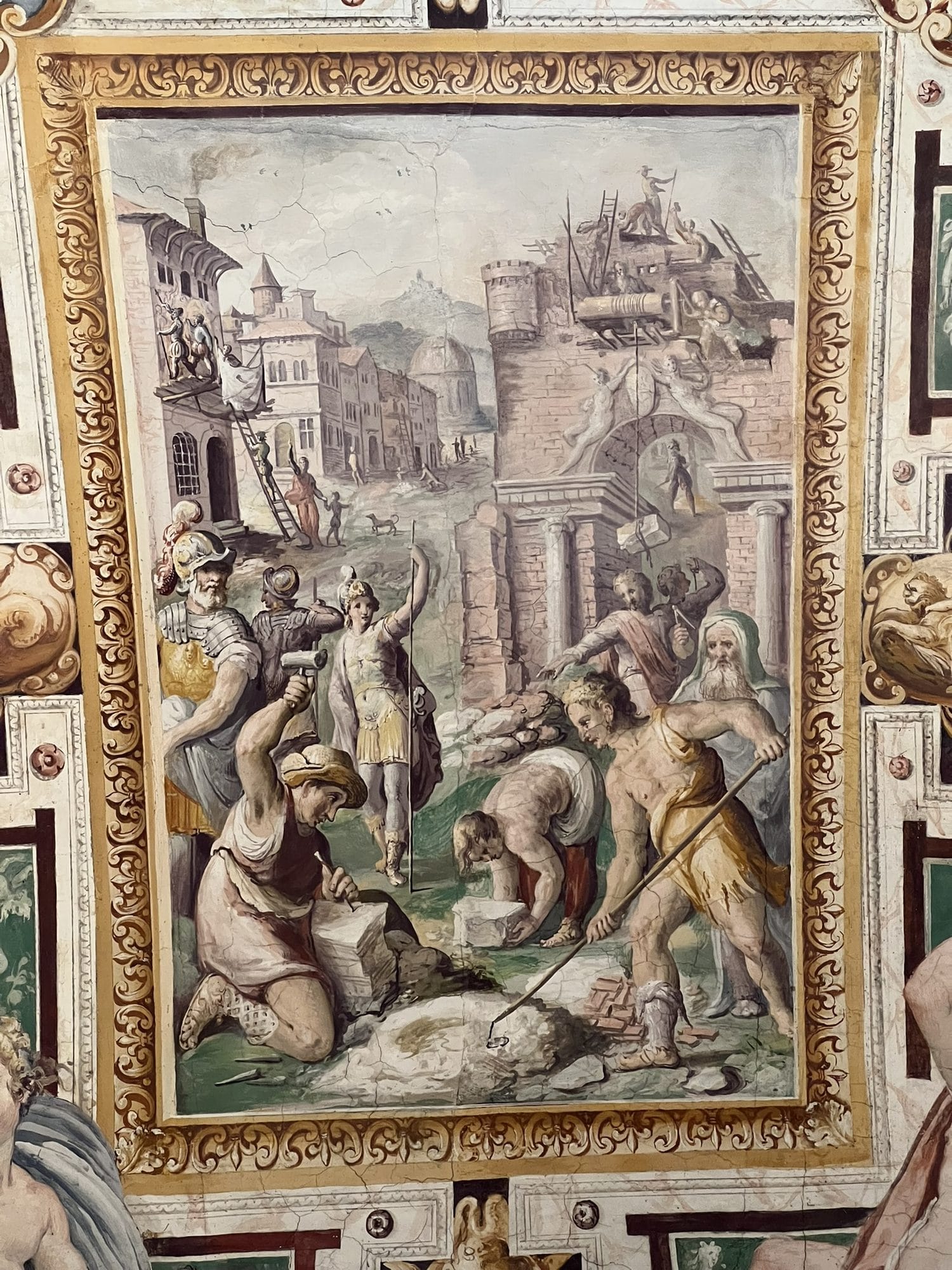 Fresco of stonecutters working on stone blocks, men with levers, ladders and a winch on the walls of a city under construction