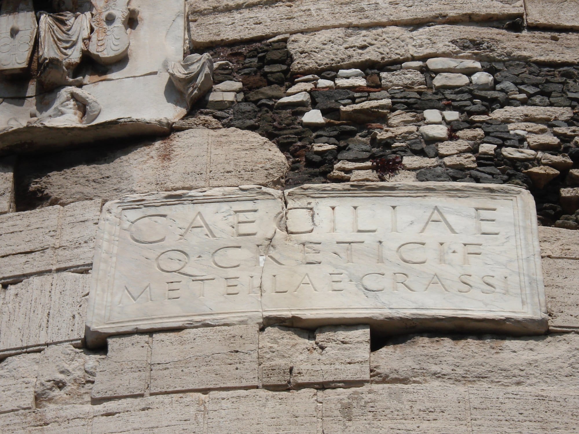 A marble slab set into the travertine of the tomb, carved in Roman capitals with the names of Caecilia Metella, her father Creticus and her husband Crassus