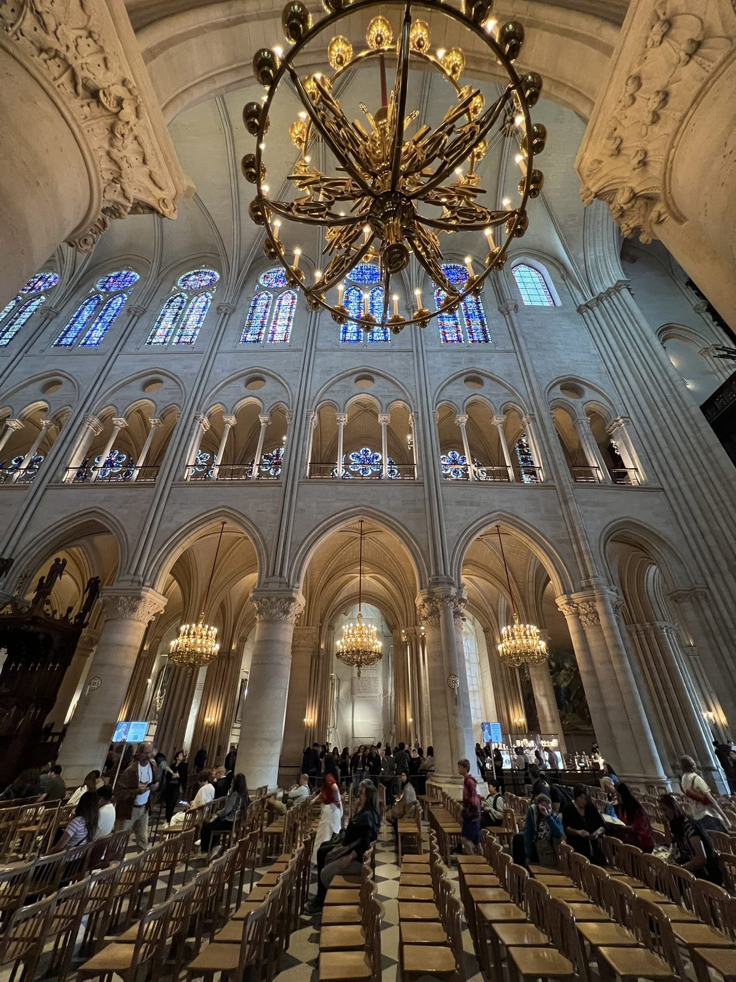 The three-level elevation of the nave of Notre-Dame, with a large circular chandelier in the foreground and blue stained glass at the top