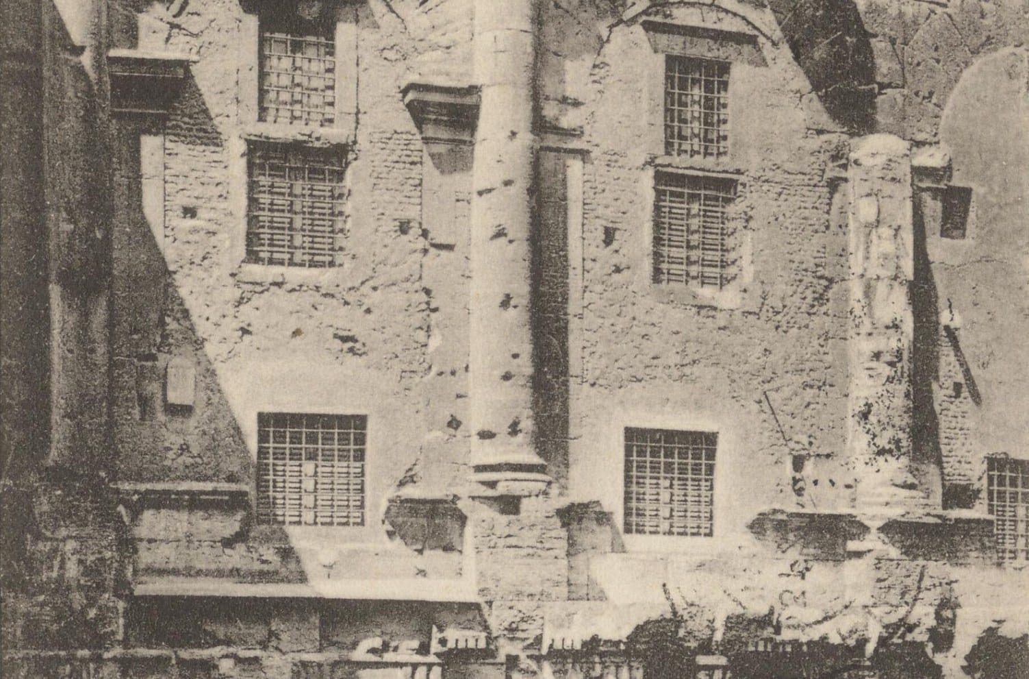 Old postcard showing the weathered stone arches and half-columns of the Theatre of Marcellus, walled in and pierced by windows with iron grilles